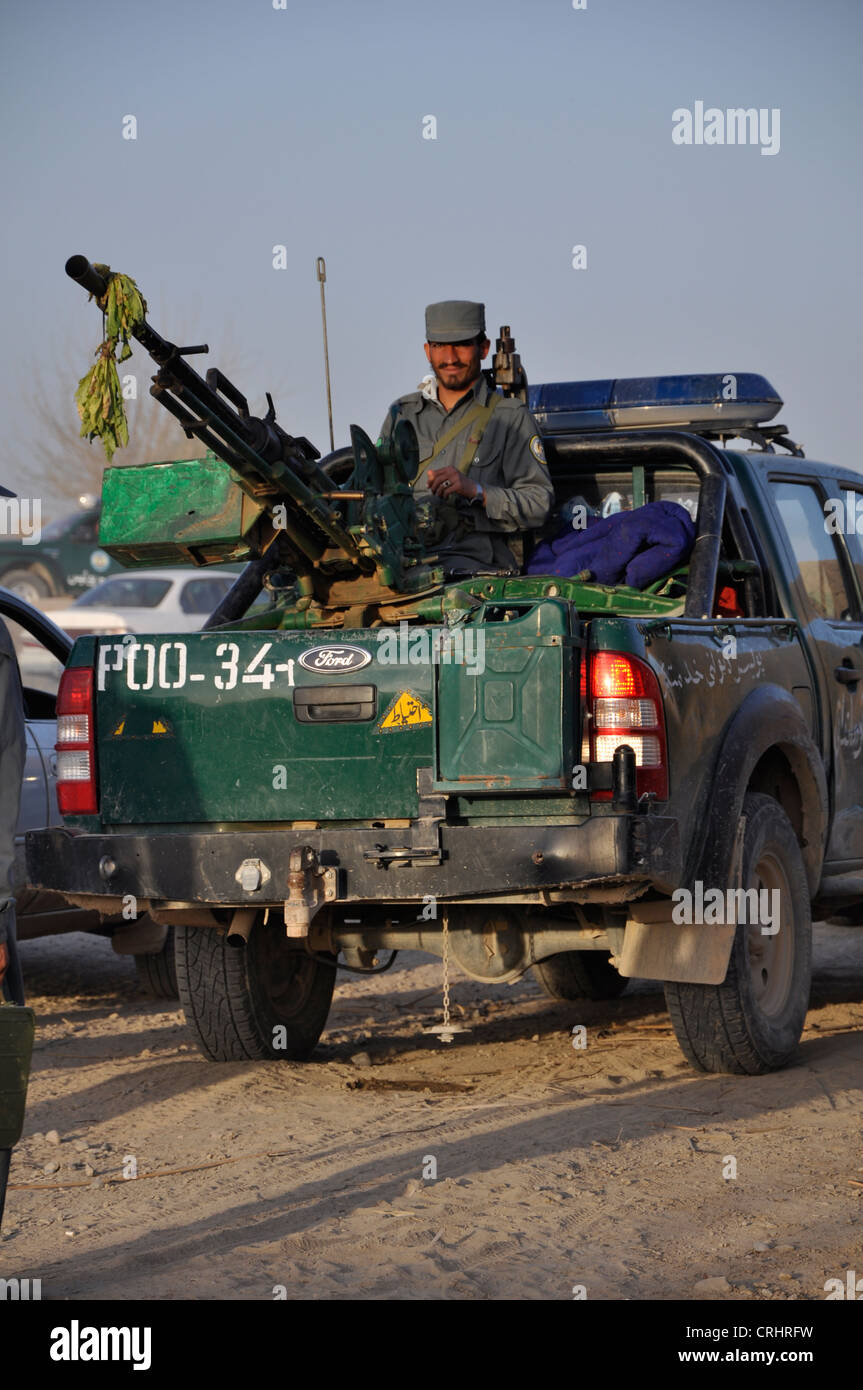 Un lapidato poliziotto afghano pone con una massa alla pistola ad aria montato sul retro di un pickup, registrati POO. Foto Stock
