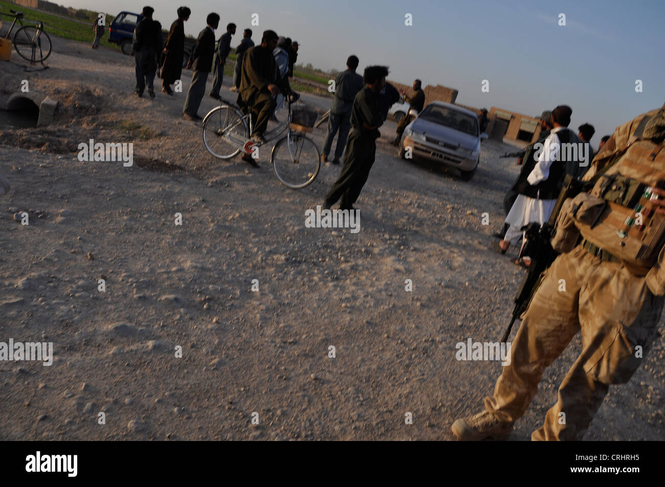 La gente del posto si riuniscono intorno a un posto di blocco militare in Afghanistan Foto Stock