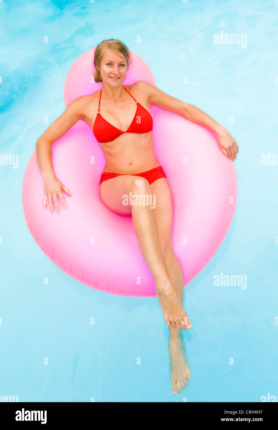 Giovane donna attraente su airbed in piscina Foto Stock