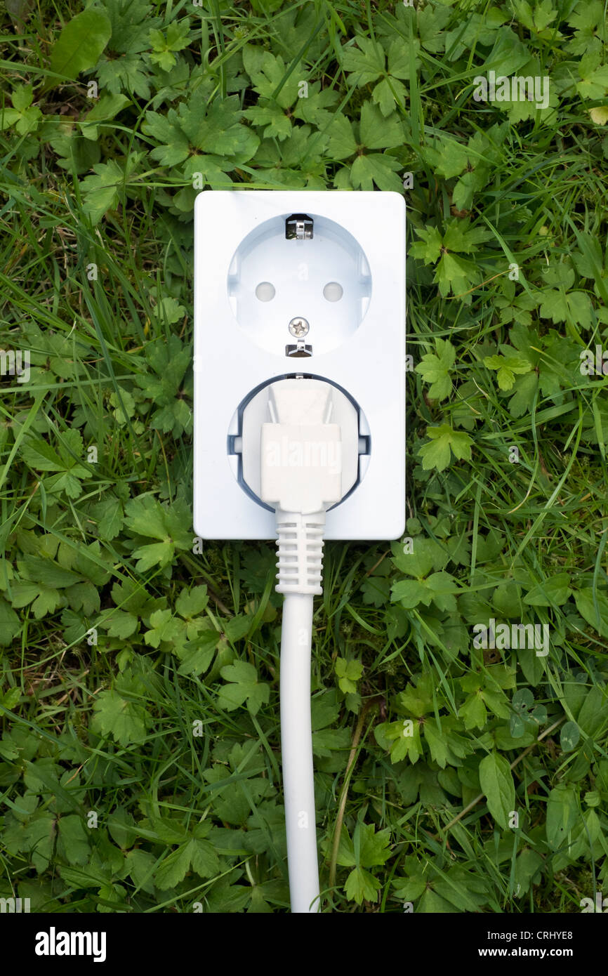 Presa elettrica sul concetto di erba verde e pulita di alimentazione di energia Foto Stock