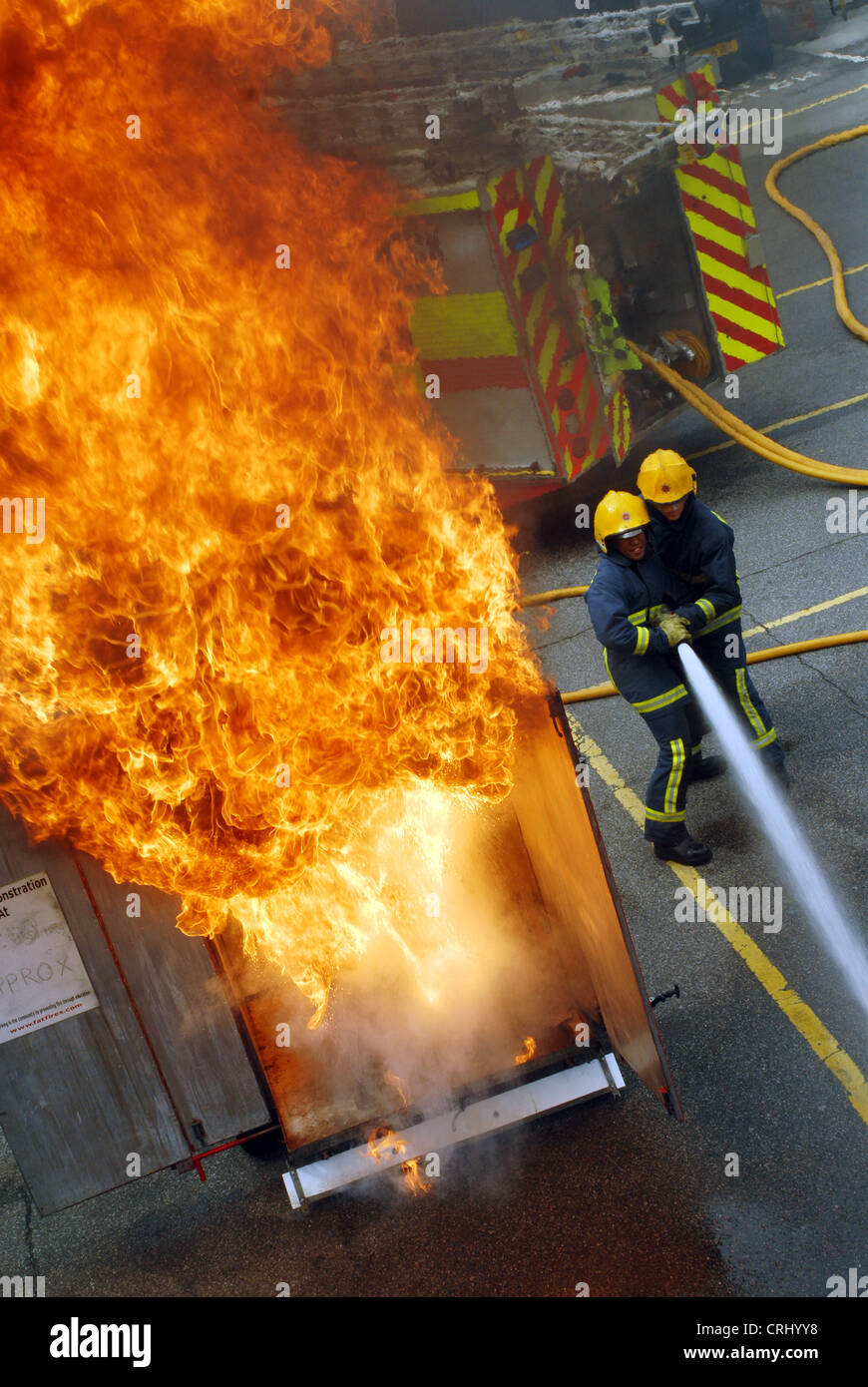 Una dimostrazione dei pericoli di una padella fuoco. I vigili del fuoco tentativo di spegnere le fiamme. Foto Stock