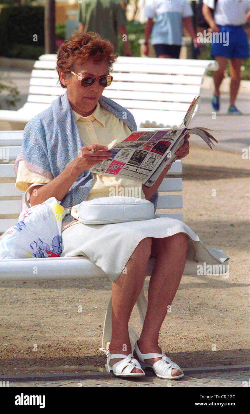 Una donna sul lungomare, leggendo il giornale Foto Stock