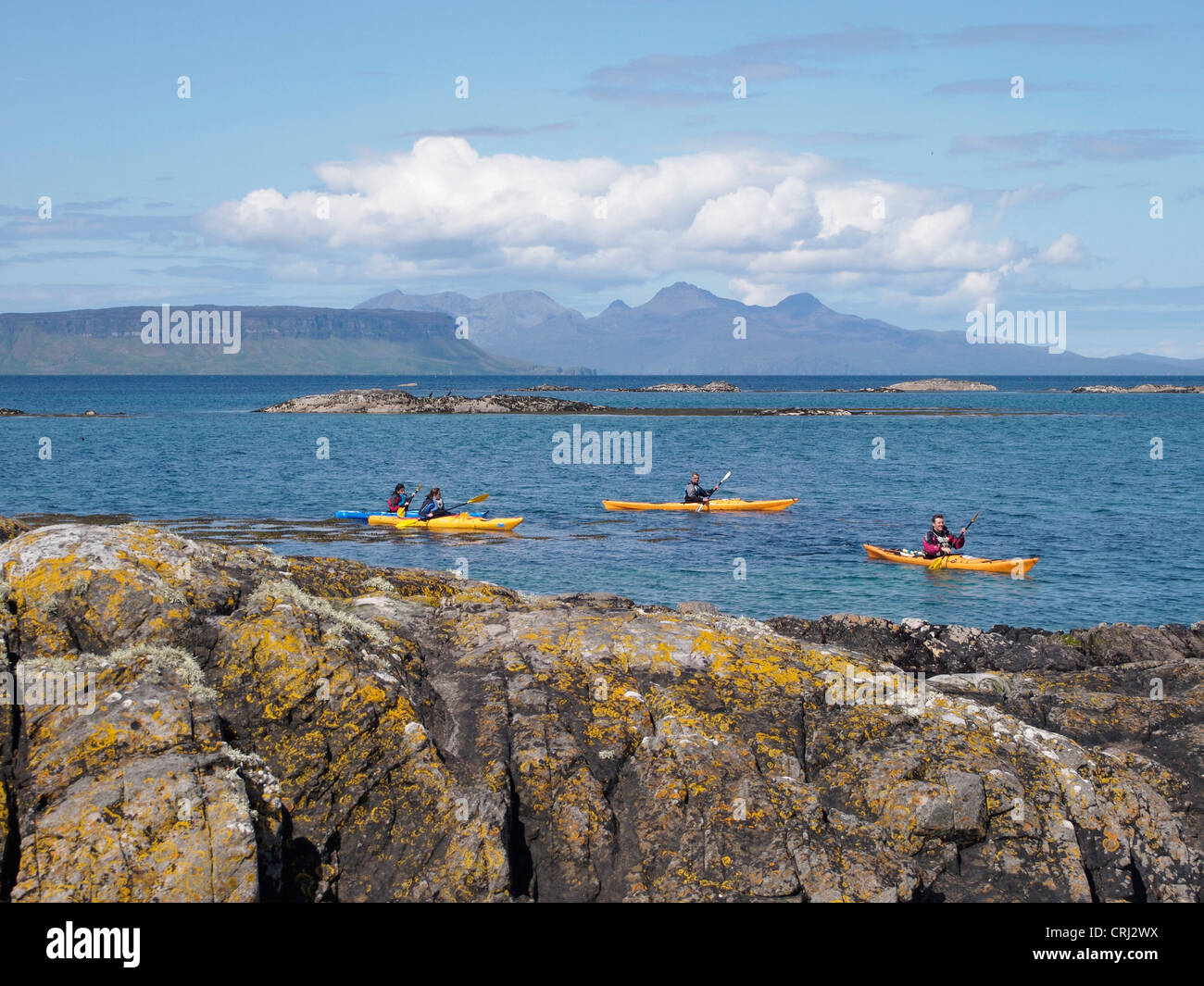 Kayak di mare tra la skerries, Arisaig, Scozia con Rum dietro Foto Stock