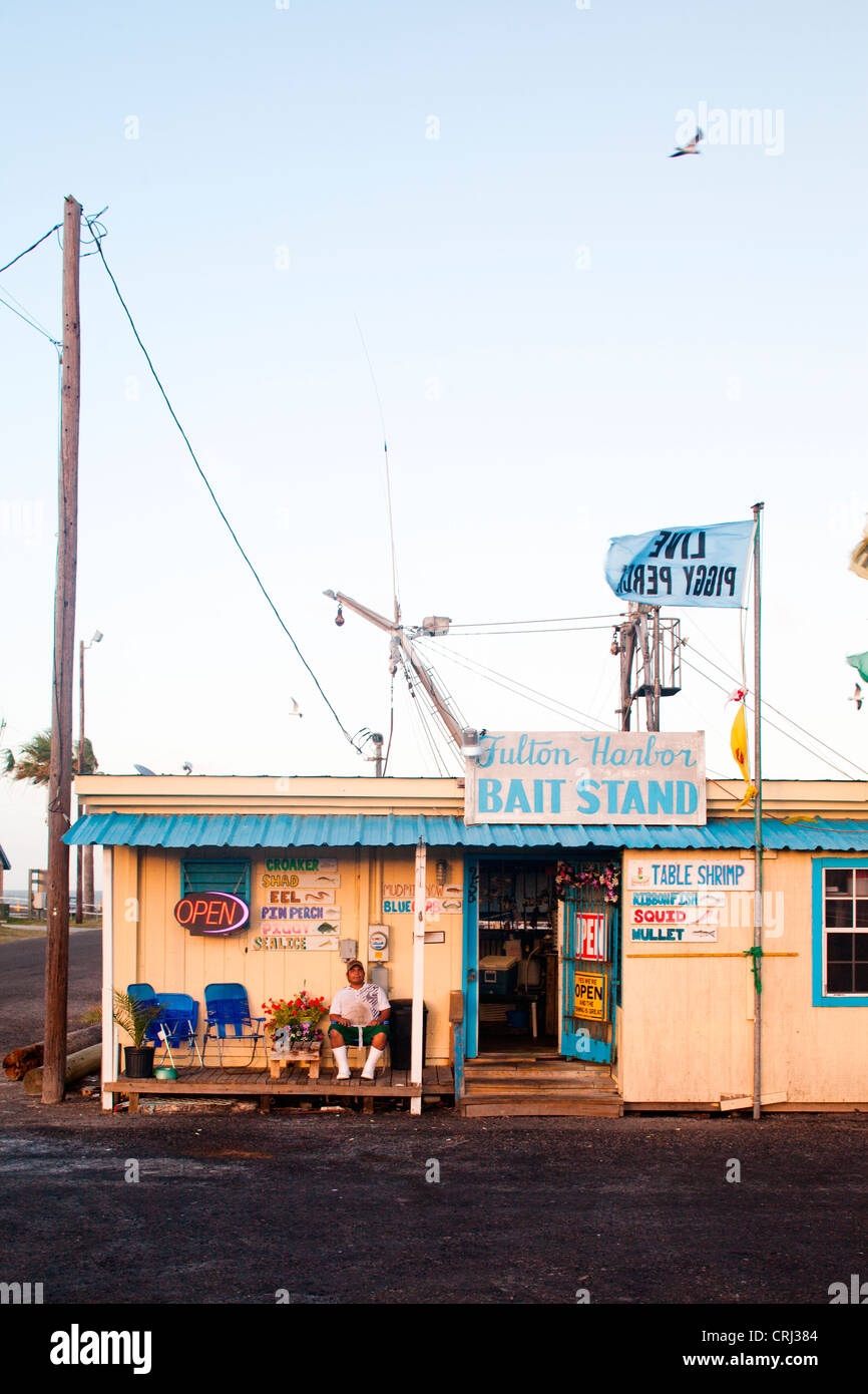 Un giovane uomo che indossa scarponi si siede di fronte a una esca shack. Foto Stock