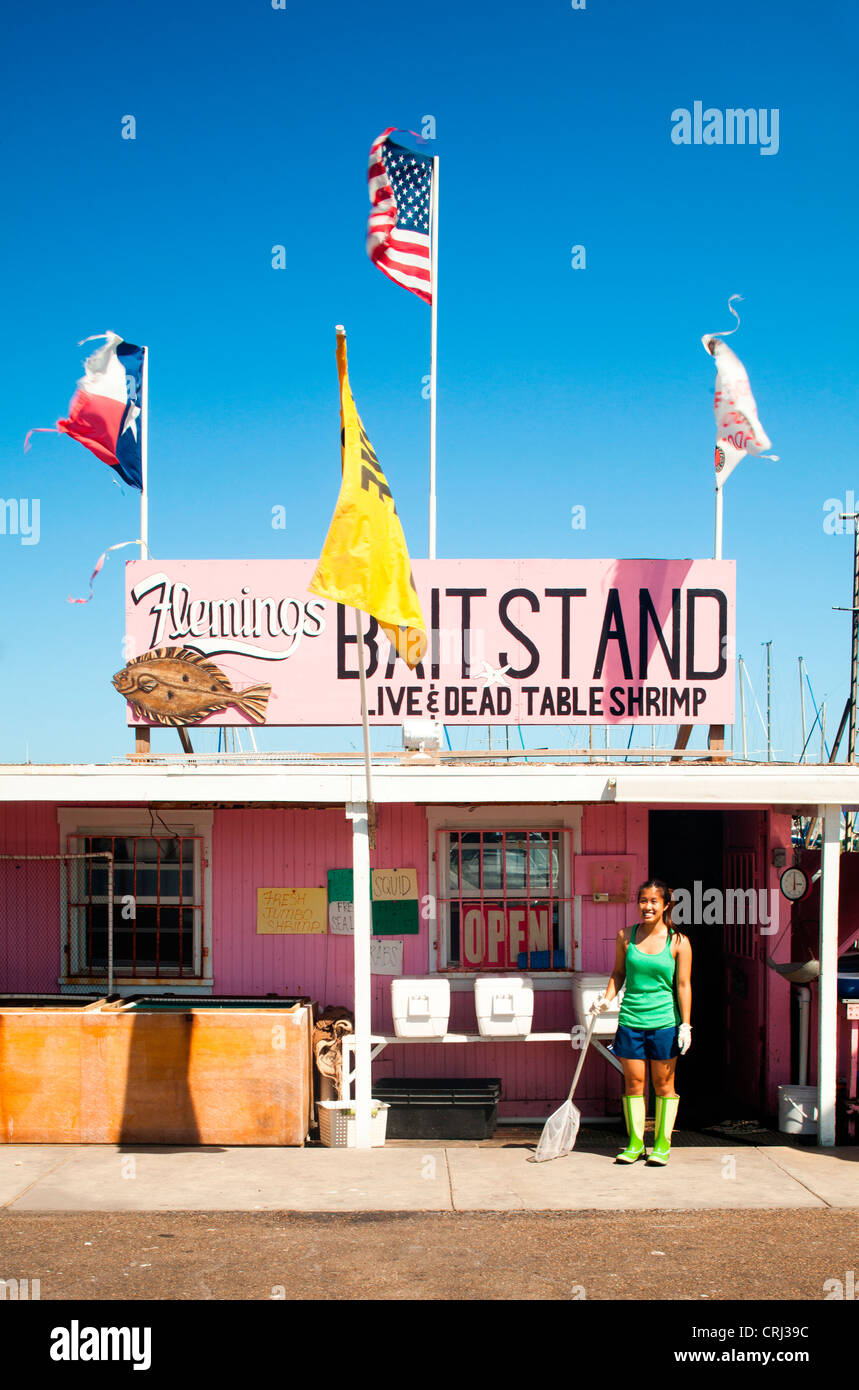 Una giovane donna che indossa scarponi sta in piedi di fronte ad un'esca shack su una giornata di sole sorride alla telecamera. Foto Stock