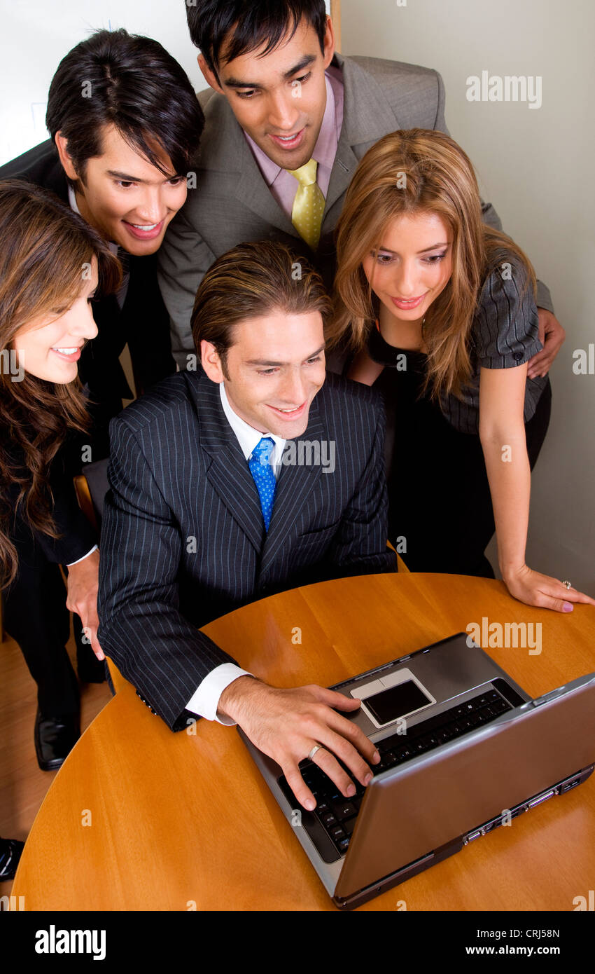 5 sorridente young business persone che guardano un notebook Foto Stock