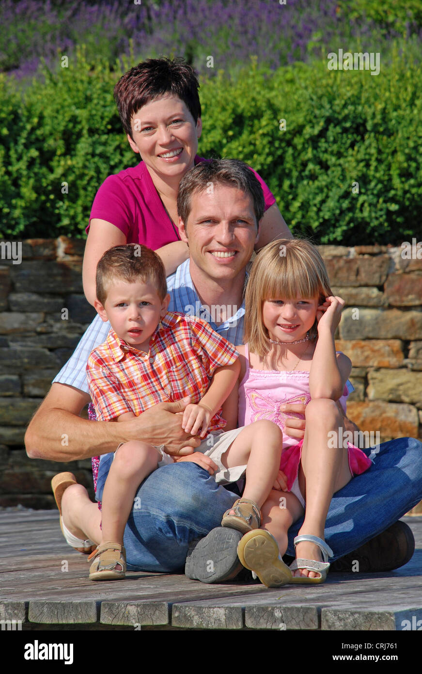 Giovane famiglia con due bambini seduti sul Boardwalk Foto Stock