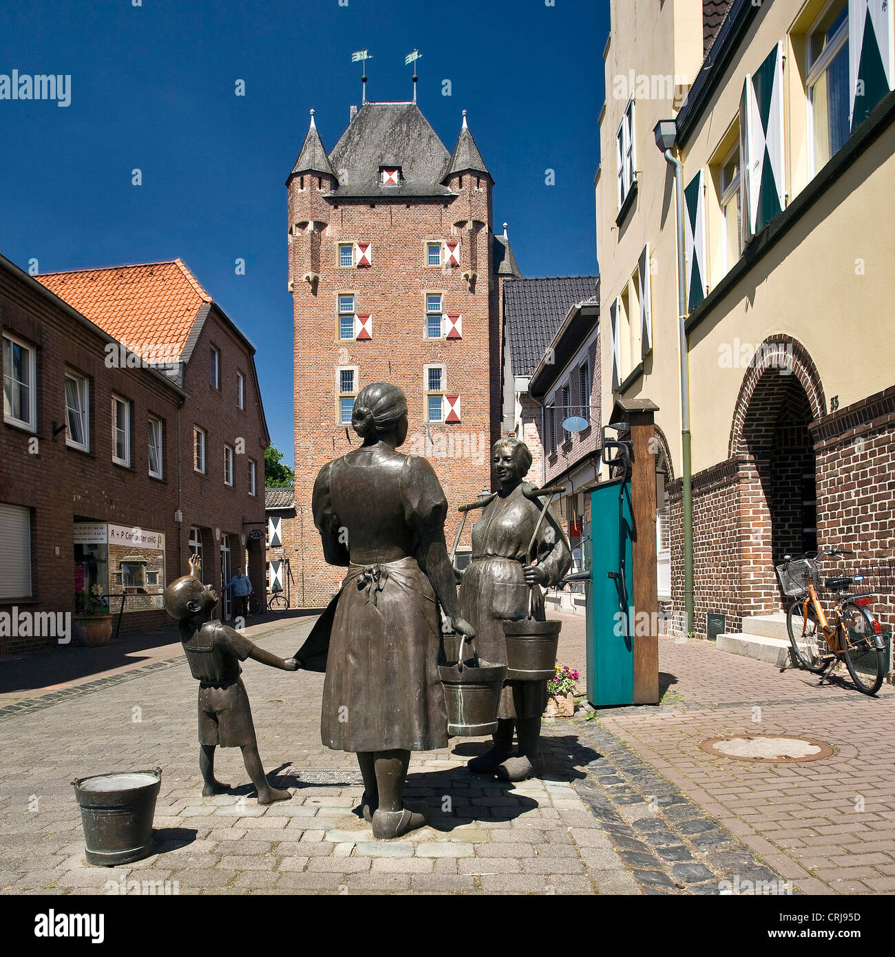 Scultura di donne a una pompa per acqua nella città di Xanten, Porta di Kleve, Klever Tor, in background, in Germania, in Renania settentrionale-Vestfalia, Xanten Foto Stock