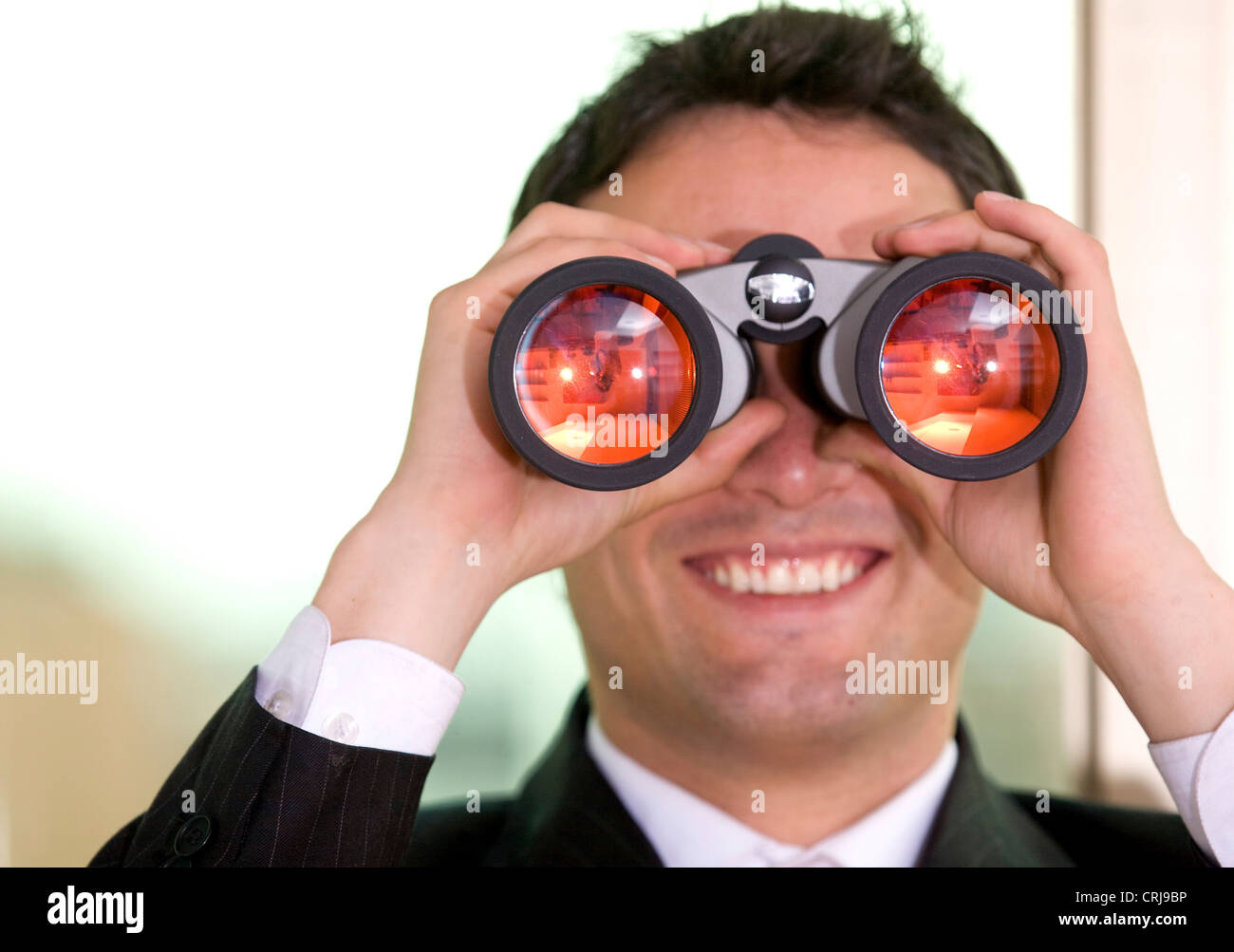 Imprenditore cerca attraverso il binocolo con un sorriso Foto Stock