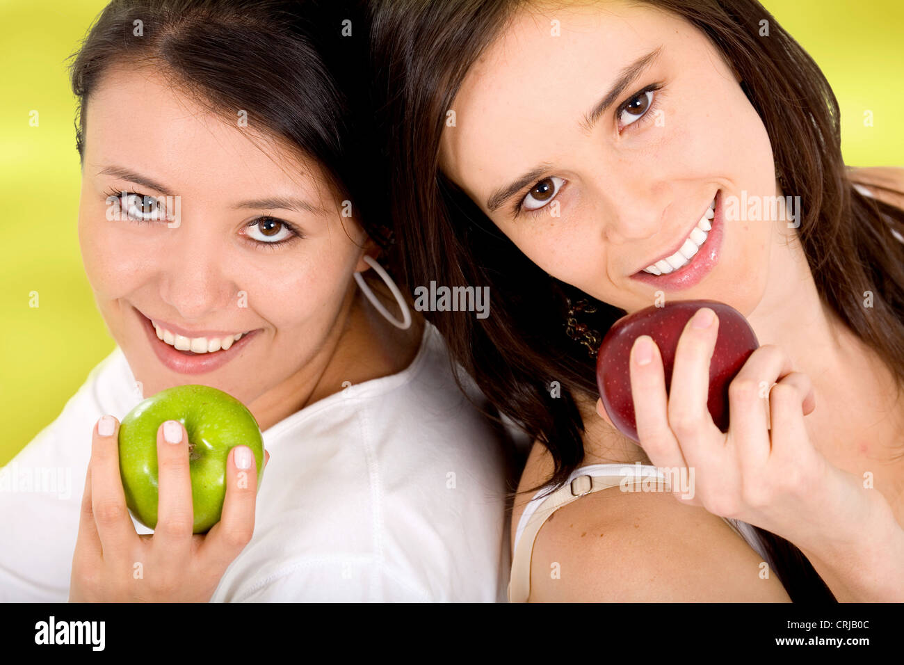 Due giovani donne, una con il verde e l'altra con ared apple Foto Stock