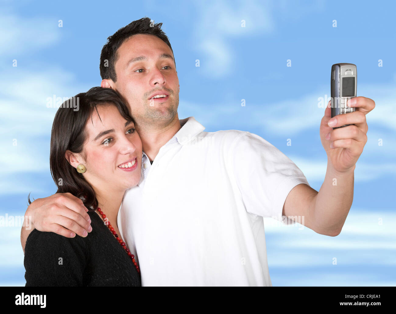 Giovane prendendo un pic con un telefono cellulare dotato di sky in background Foto Stock