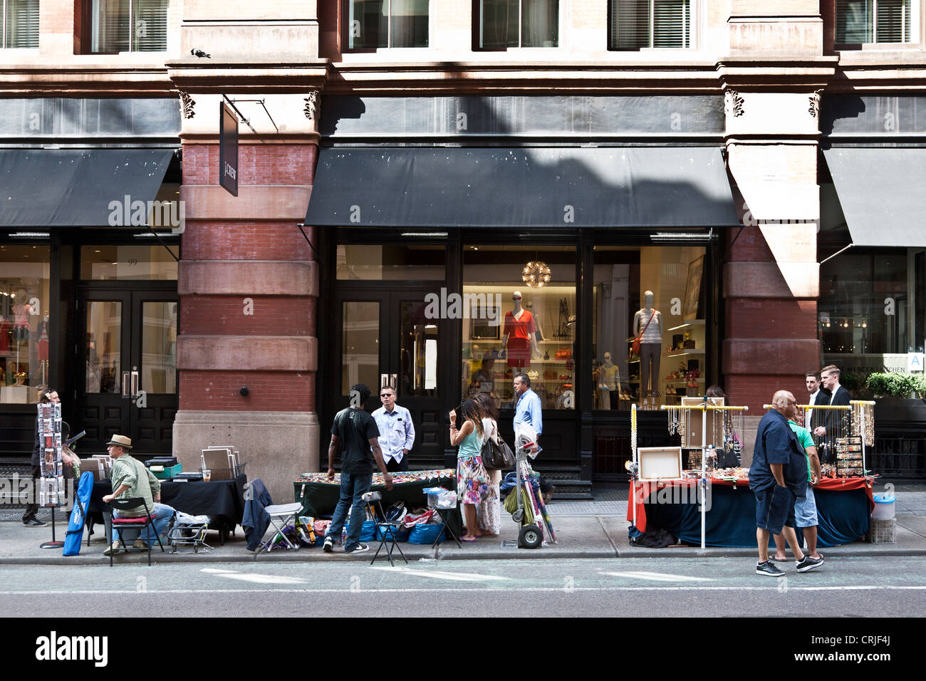 Marciapiede temporaneo fornitori forniscono un colorati negozi alternativa ai grandi boutique dietro di loro n quartiere di Soho NYC Foto Stock