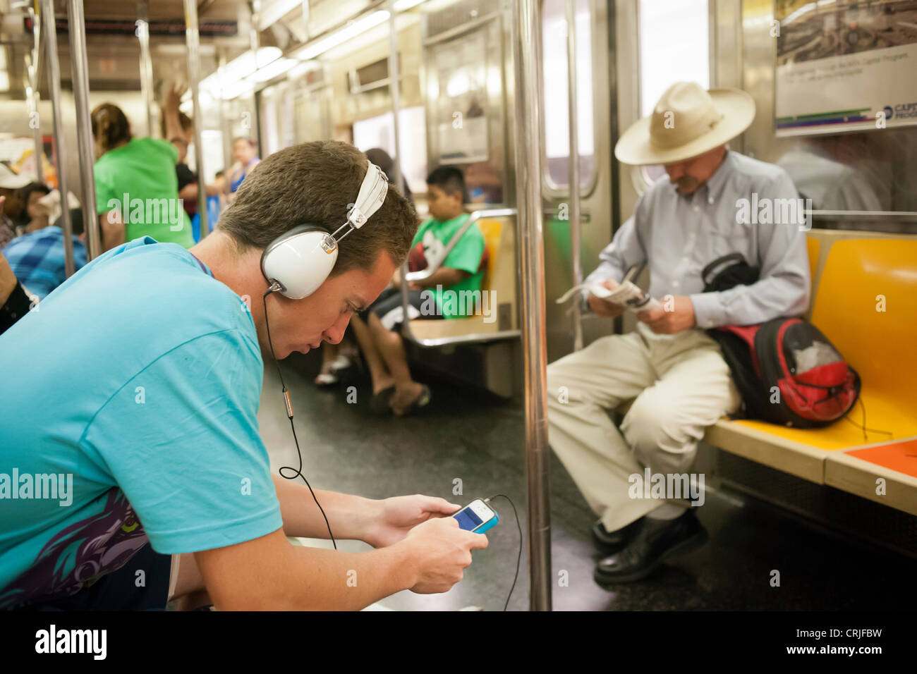 Un ascoltatore di musica indossa la sua oltre le cuffie auricolari in un vagone della metropolitana di New York Foto Stock