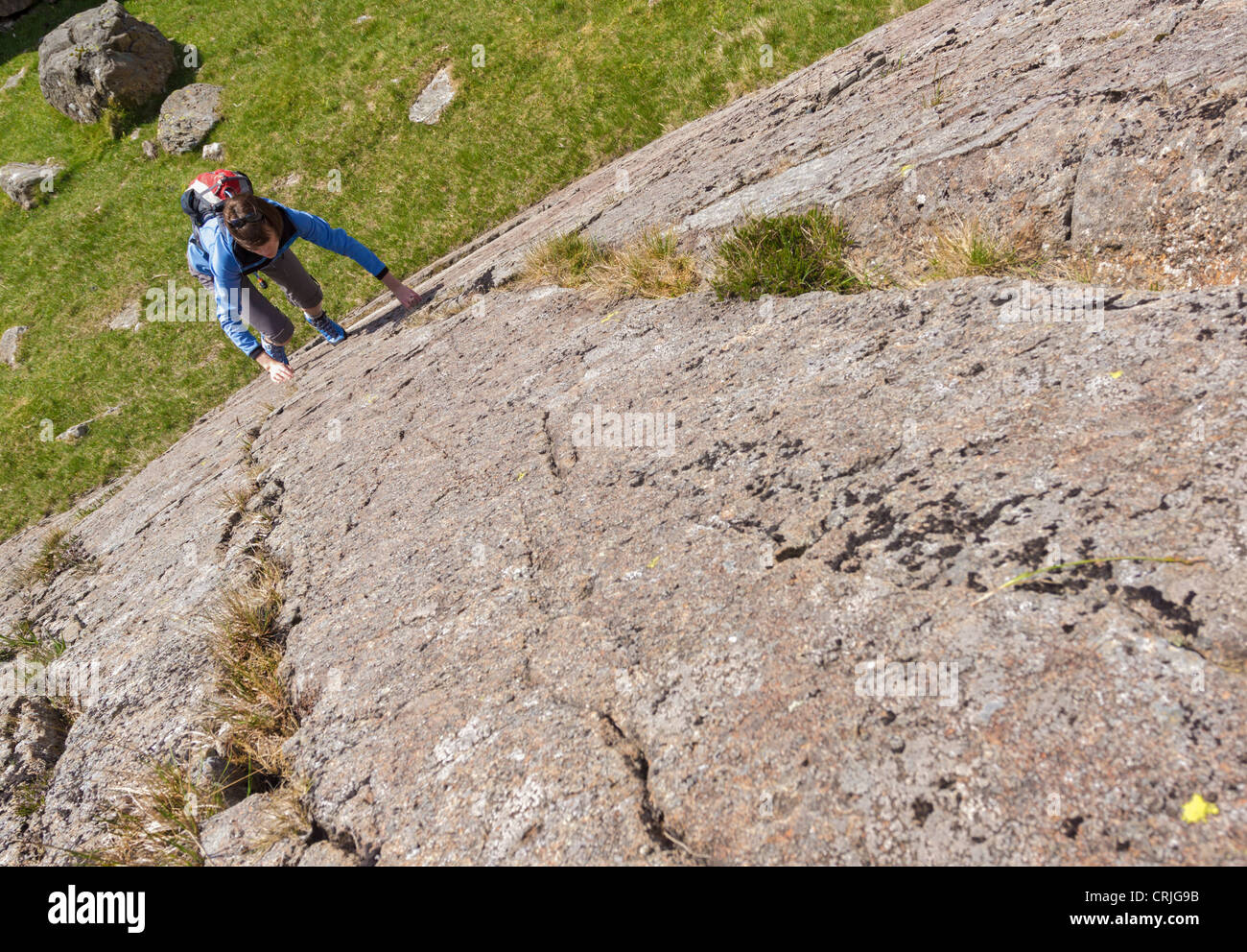 Female Rock scrambler salendo Seathwaite lastre, Lake District, UK. Foto Stock