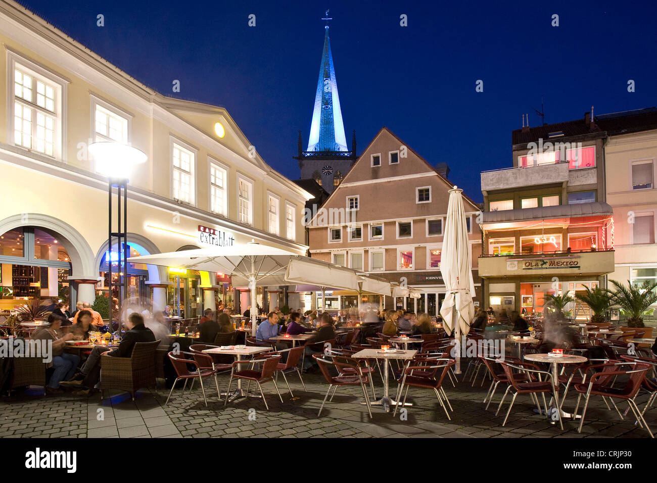 Persone siiting in un ristorante di strada sul mercato di Unna al blue ora, la torre illuminata chiesa Stadtkirche, in background, in Germania, in Renania settentrionale-Vestfalia, la zona della Ruhr, Unna Foto Stock