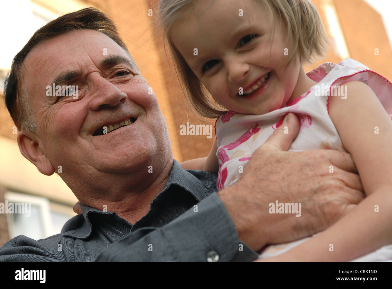 Un uomo anziano porta un bambino sulla sua spalla. Foto Stock