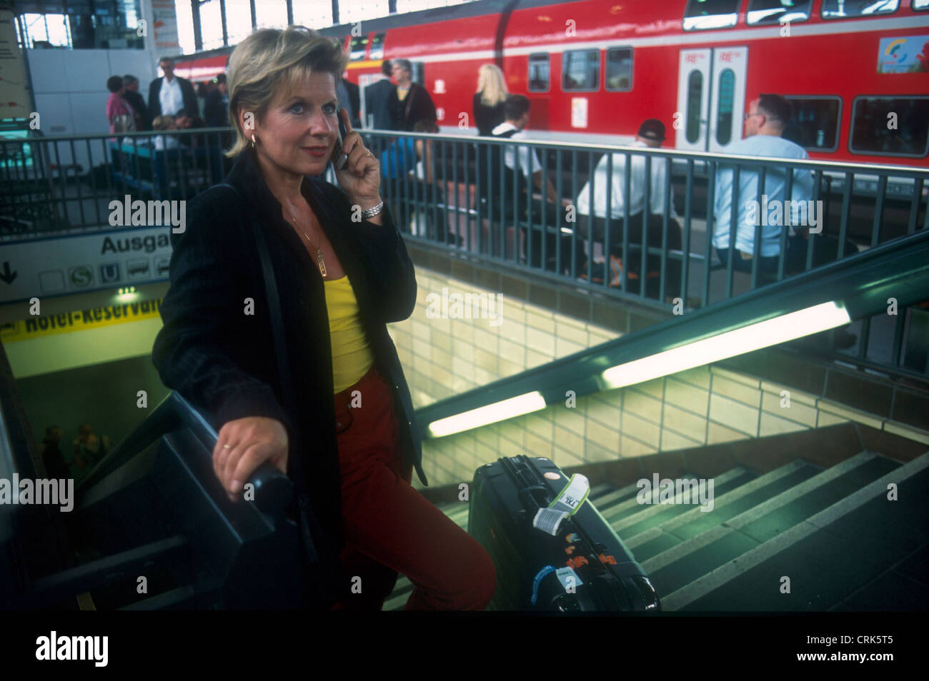 Donna con telefono mobile e bagagli sulla piattaforma Zoo Foto Stock