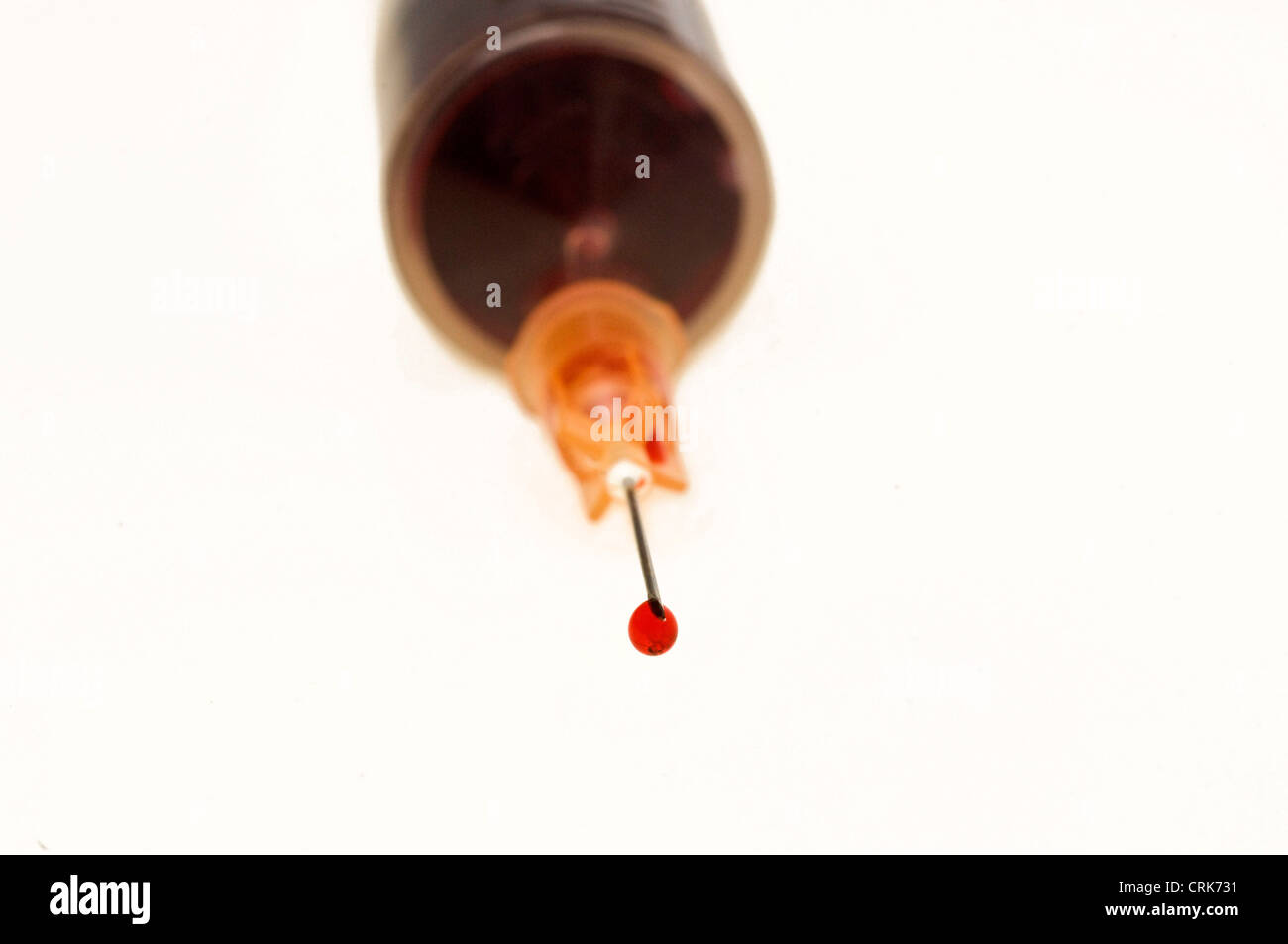 Vista di un ago fissato ad una siringa, la punta dell'ago contiene una gocciolina di liquido. Foto Stock