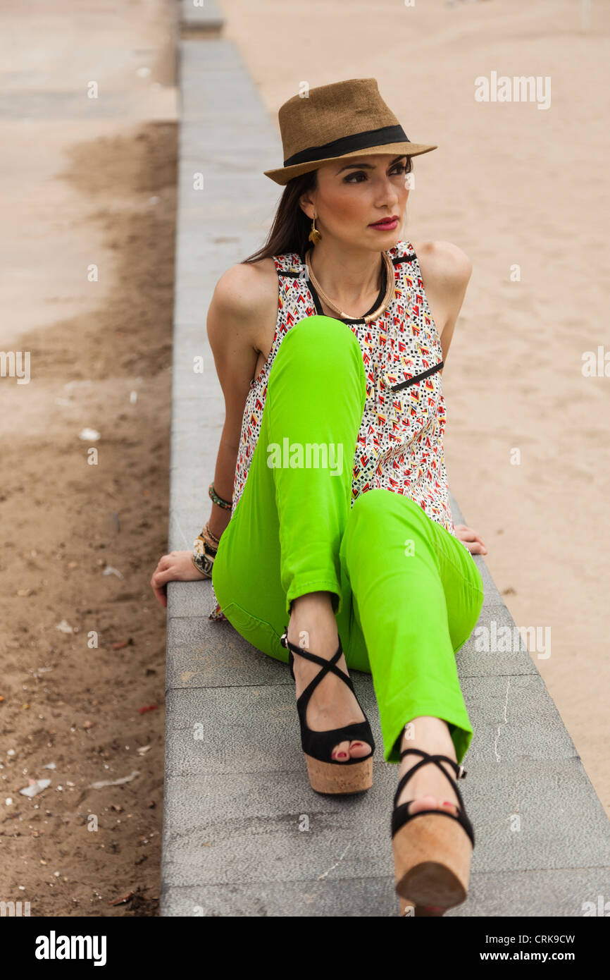 Modello con hat seduta su una panchina vicino alla spiaggia Foto Stock