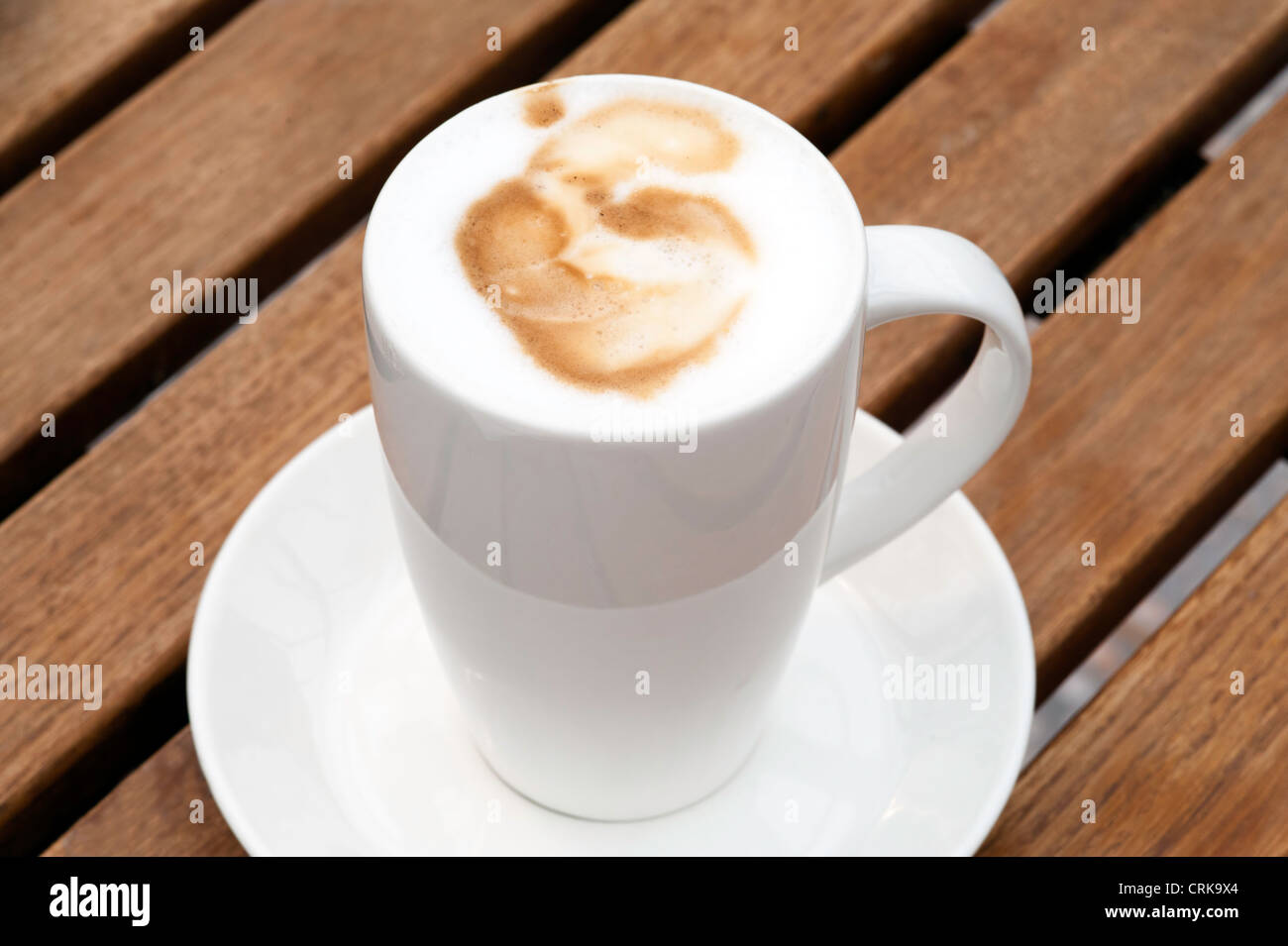 Freschi e saporiti cappuccino caffè nella tazza bianca di legno sul tavolo da giardino Foto Stock