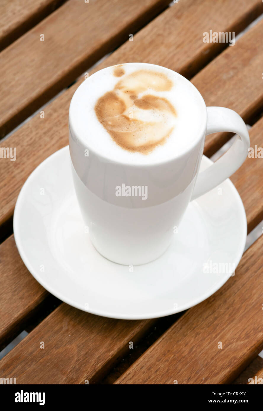 Freschi e saporiti cappuccino caffè nella tazza bianca di legno sul tavolo da giardino Foto Stock