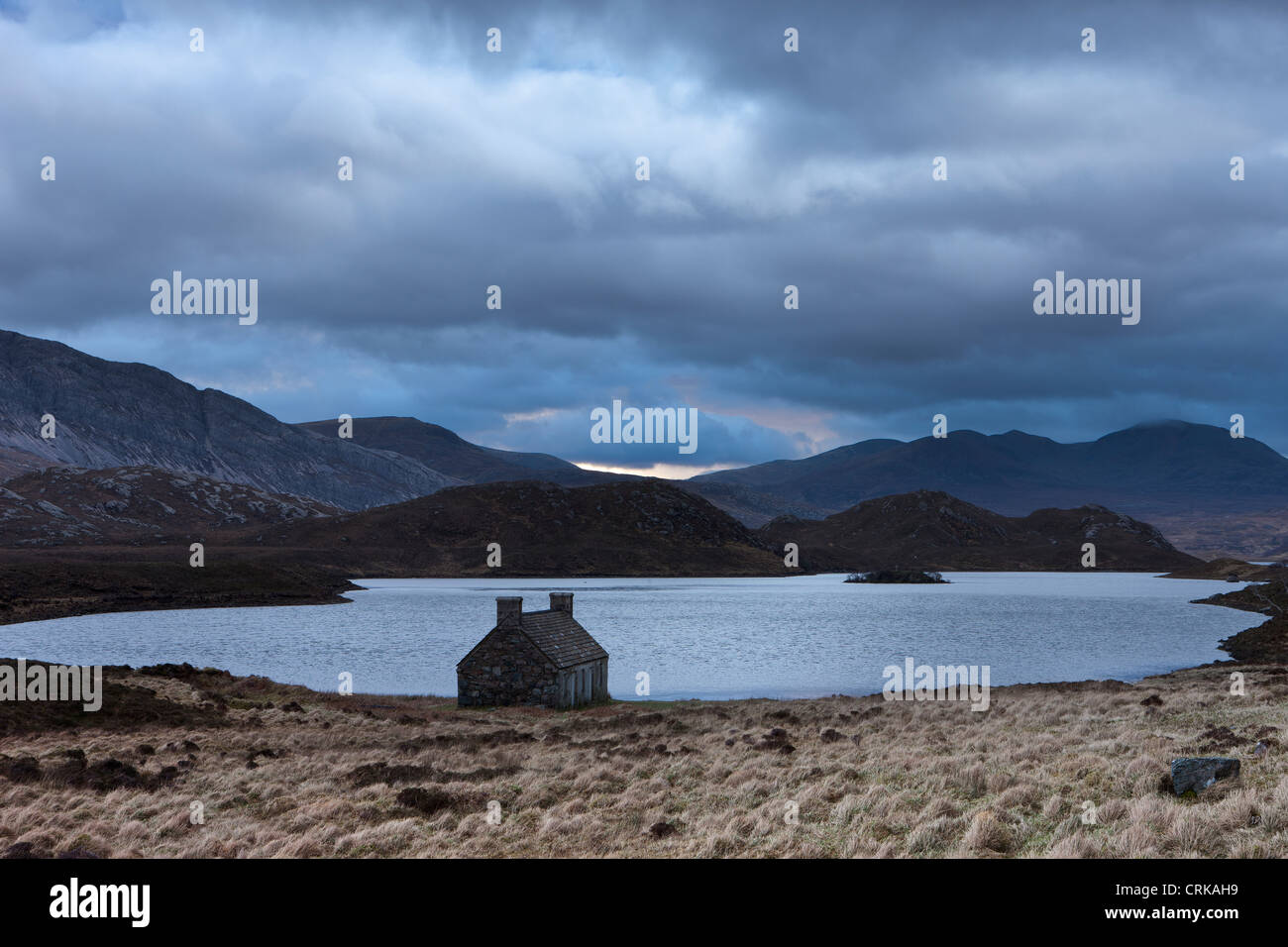 Un abbandonato crofters cottage da una lochan in Sutherland, Scozia Foto Stock