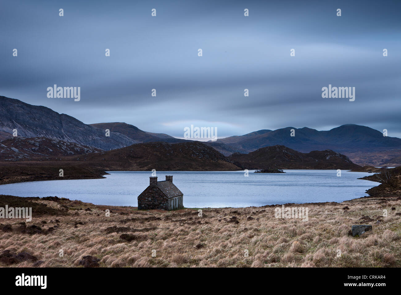 Un abbandonato crofters cottage da una lochan in Sutherland, Scozia. Foto Stock