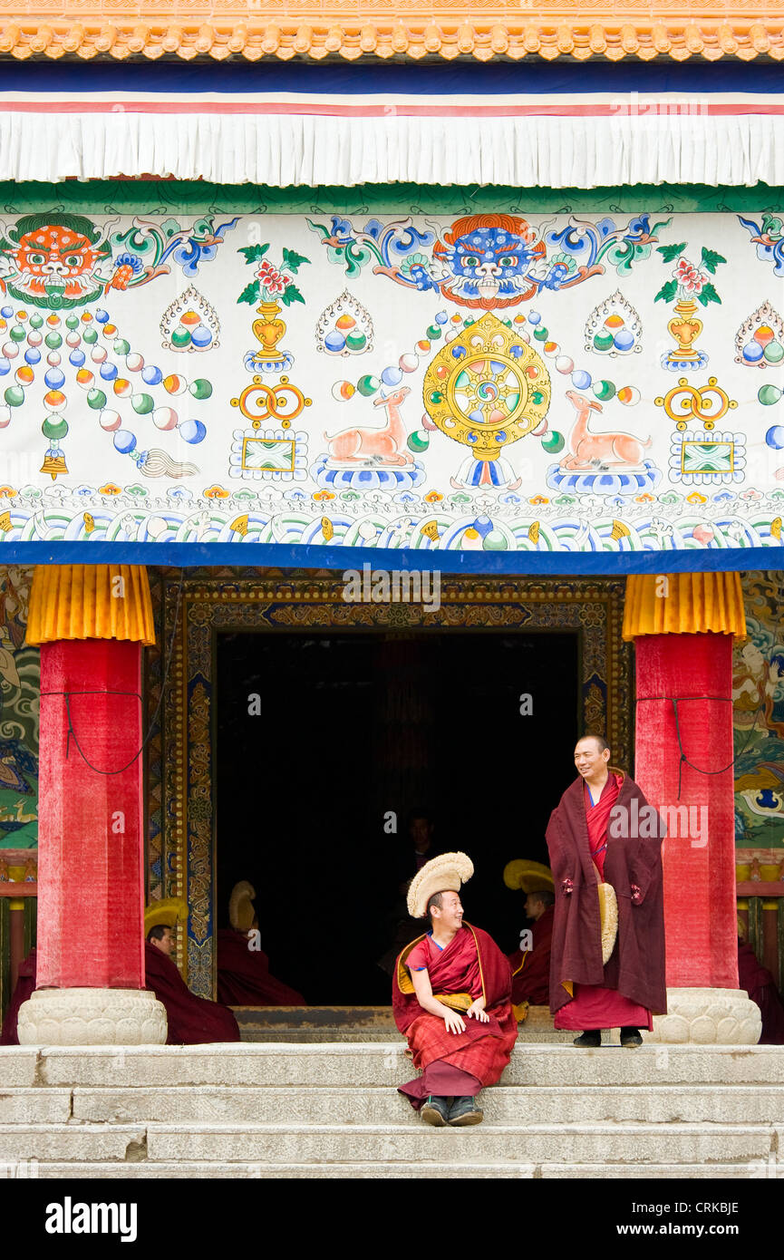 Monaci buddisti tibetani (Geluk o cappello giallo) al di fuori del Grand Hall il Sutra del monastero di Labrang prima di andare in preghiera. Foto Stock