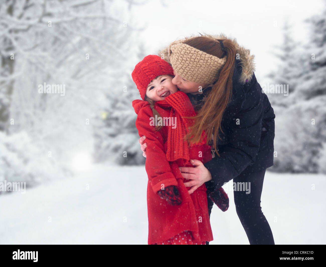 Madre e figlia baciare in neve Foto Stock