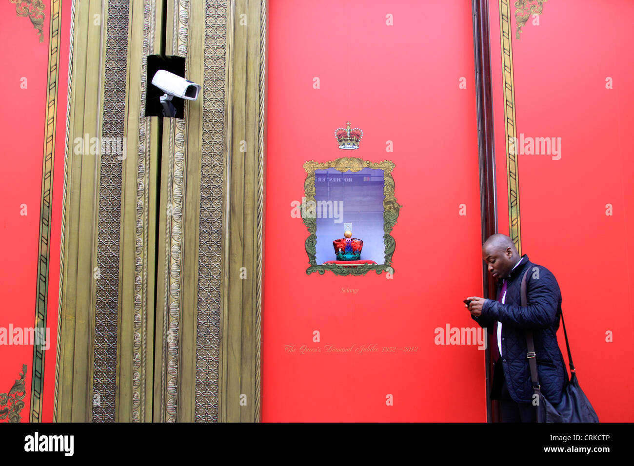 L'uomo controllando il suo telefono cellulare mentre si trova al di fuori di Harrods a Londra Foto Stock