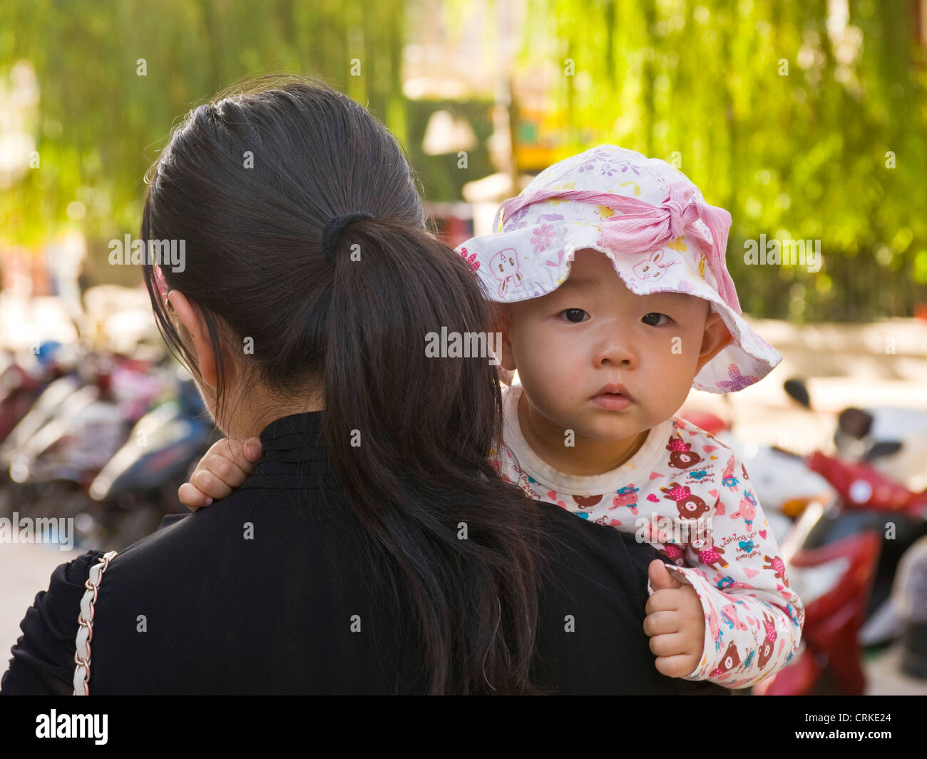 Un locale cinese madre con il suo bambino sulla sua spalla nel centro di Dunhuang. Foto Stock