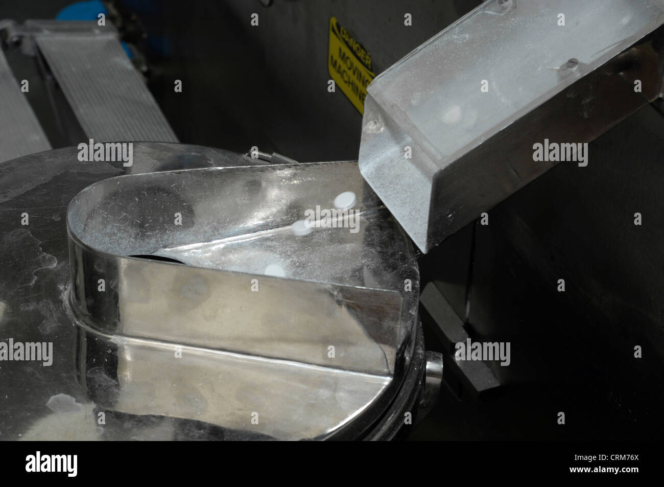 Compresse bianche versare attraverso uno scivolo durante le fasi finali della produzione di droga. Foto Stock