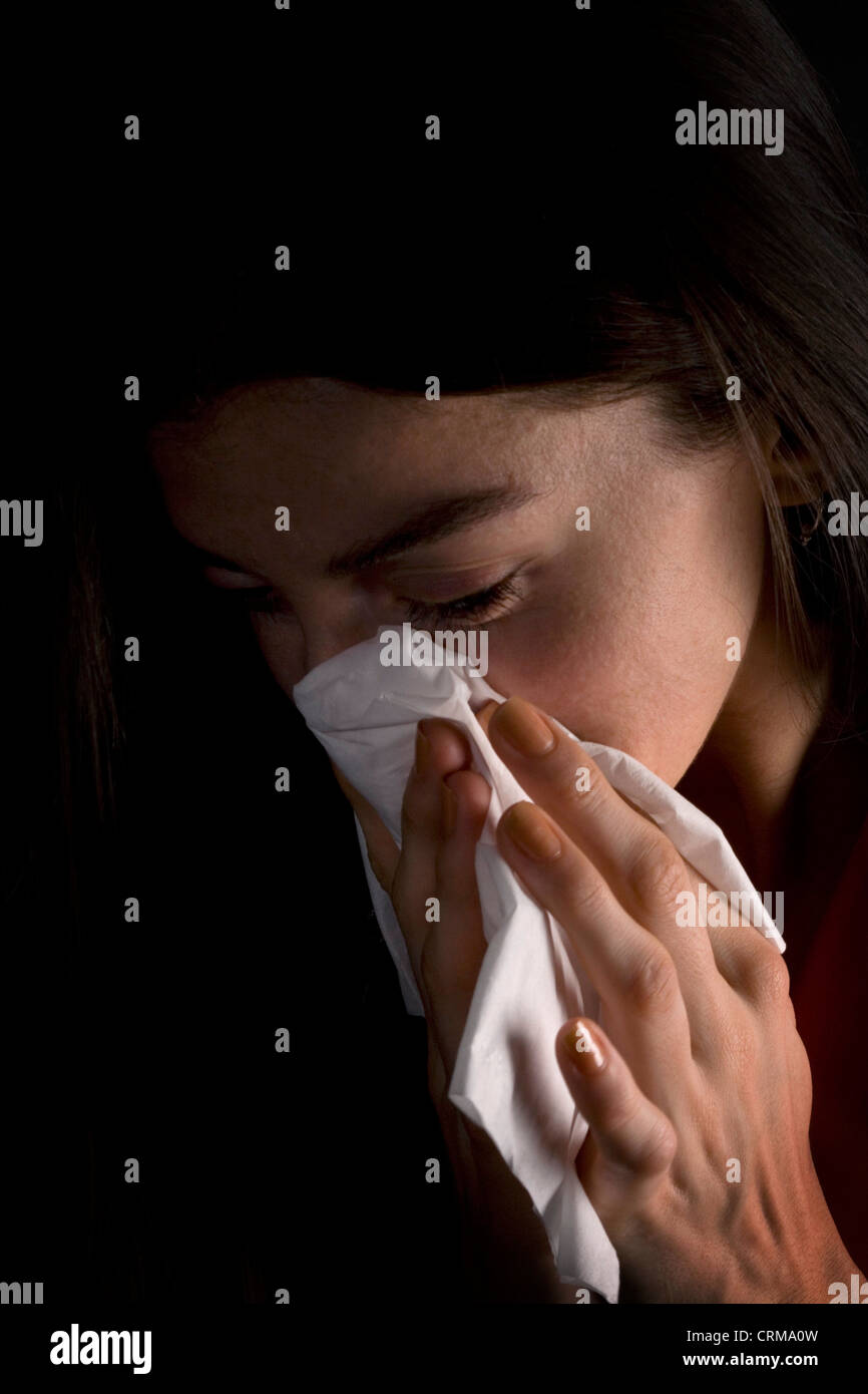 Giovane donna di starnuti ripetuti in un tessuto. Foto Stock