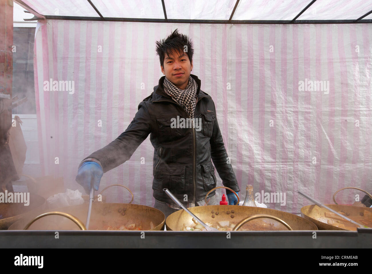 Ritratto di un giovane uomo asiatico per la cottura di cibo di strada in stallo Foto Stock