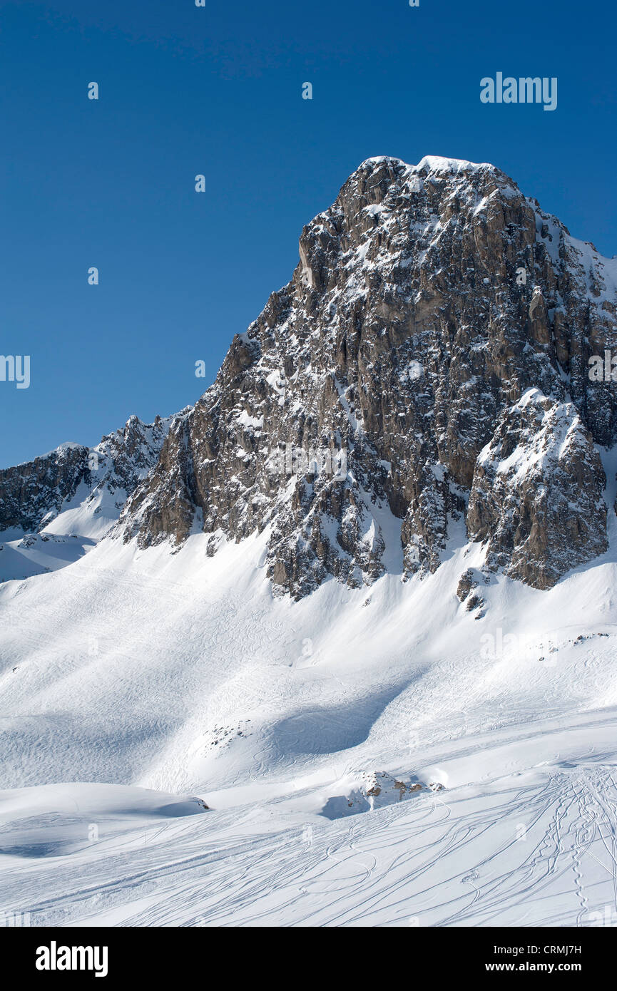Il picco di una montagna nelle Alpi francesi con neve e piste da sci Foto Stock