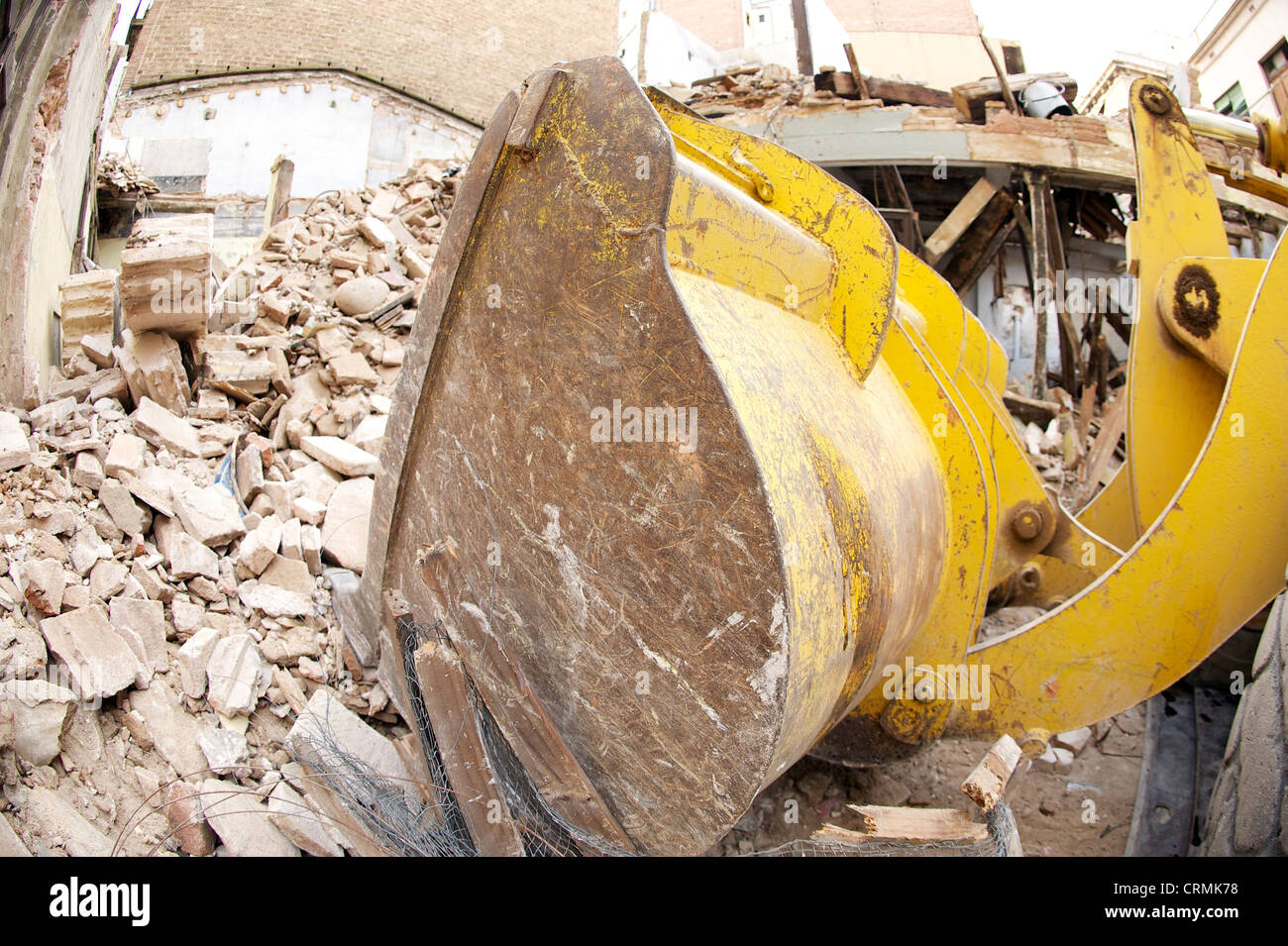 Vista laterale del giallo digger la demolizione di un edificio e deselezionando le macerie, illustrante il settore delle costruzioni in rovina, Spagna Foto Stock
