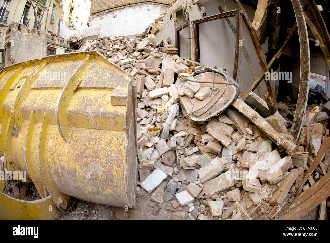 Vista laterale del giallo digger la demolizione di un edificio e deselezionando le macerie, illustrante il settore delle costruzioni in rovina, Spagna Foto Stock