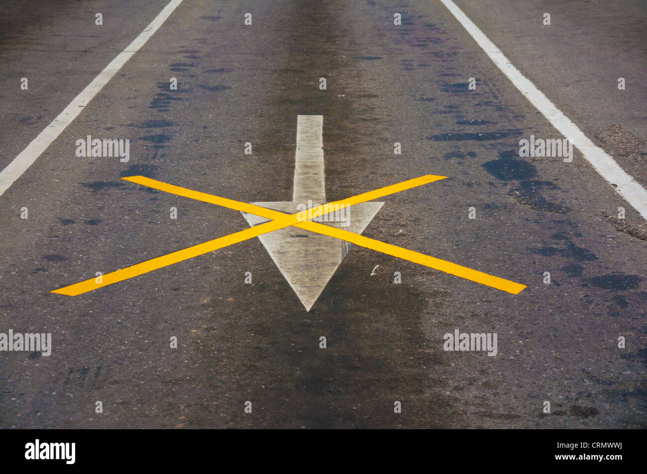 Segno di freccia e altri contrassegni sulla strada asfaltata Foto Stock