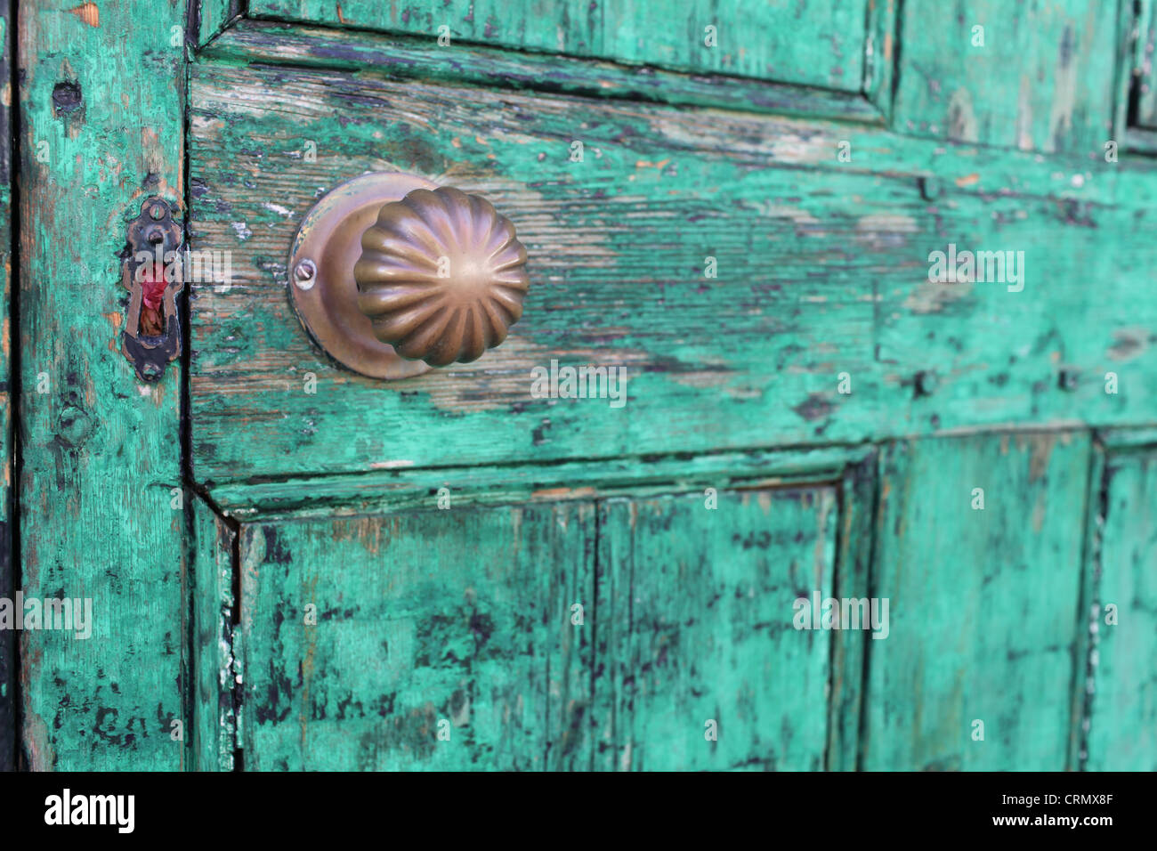 La maniglia dello sportello e la serratura su un vecchio addolorato verde porta in legno Foto Stock