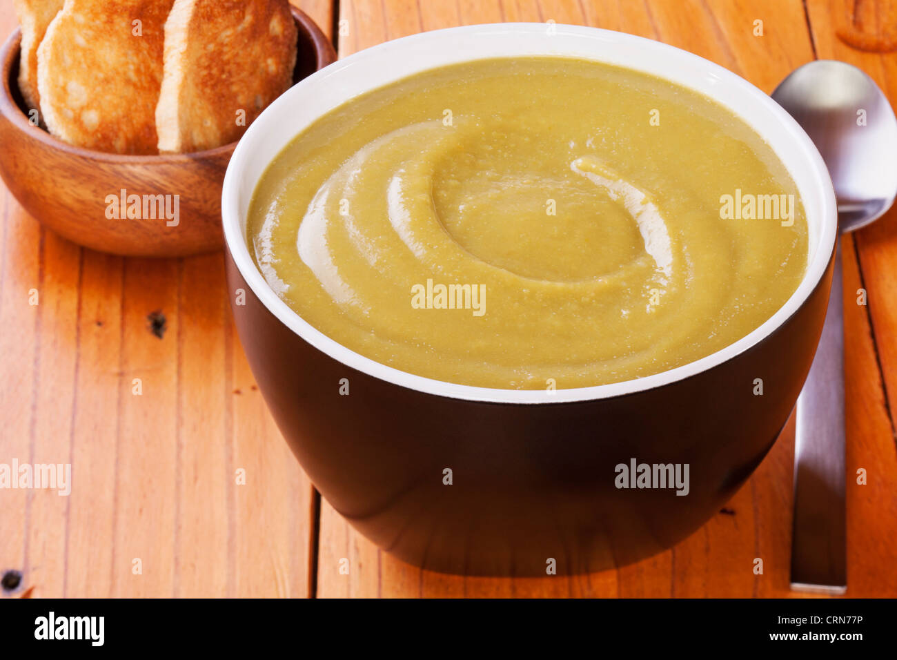 Una ciotola di spessore, pisello casalinga dividere la zuppa di piselli su un vecchio tavolo da cucina. Foto Stock