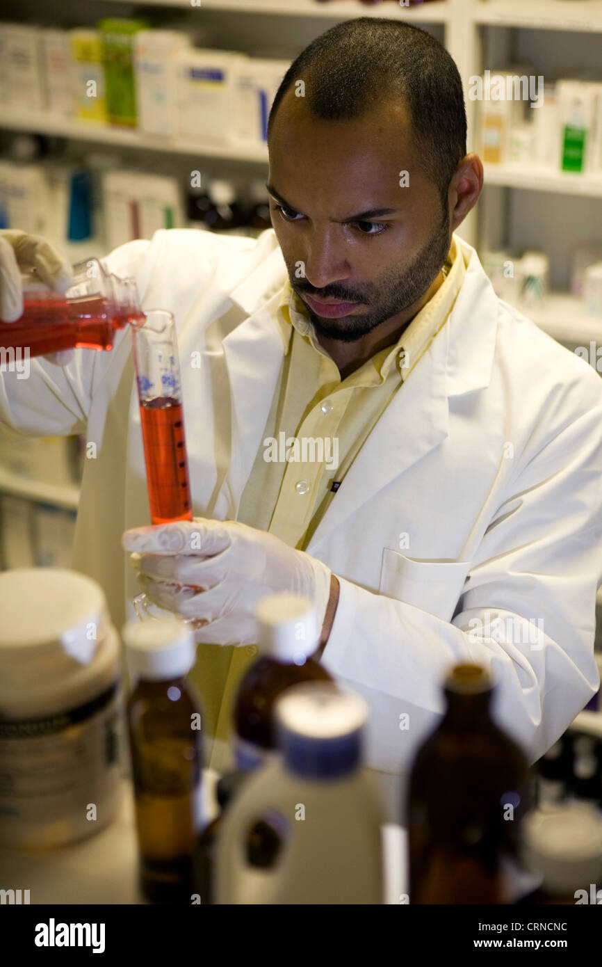 Un farmacista riversa in rosso di un liquido in un cilindro graduato. Foto Stock