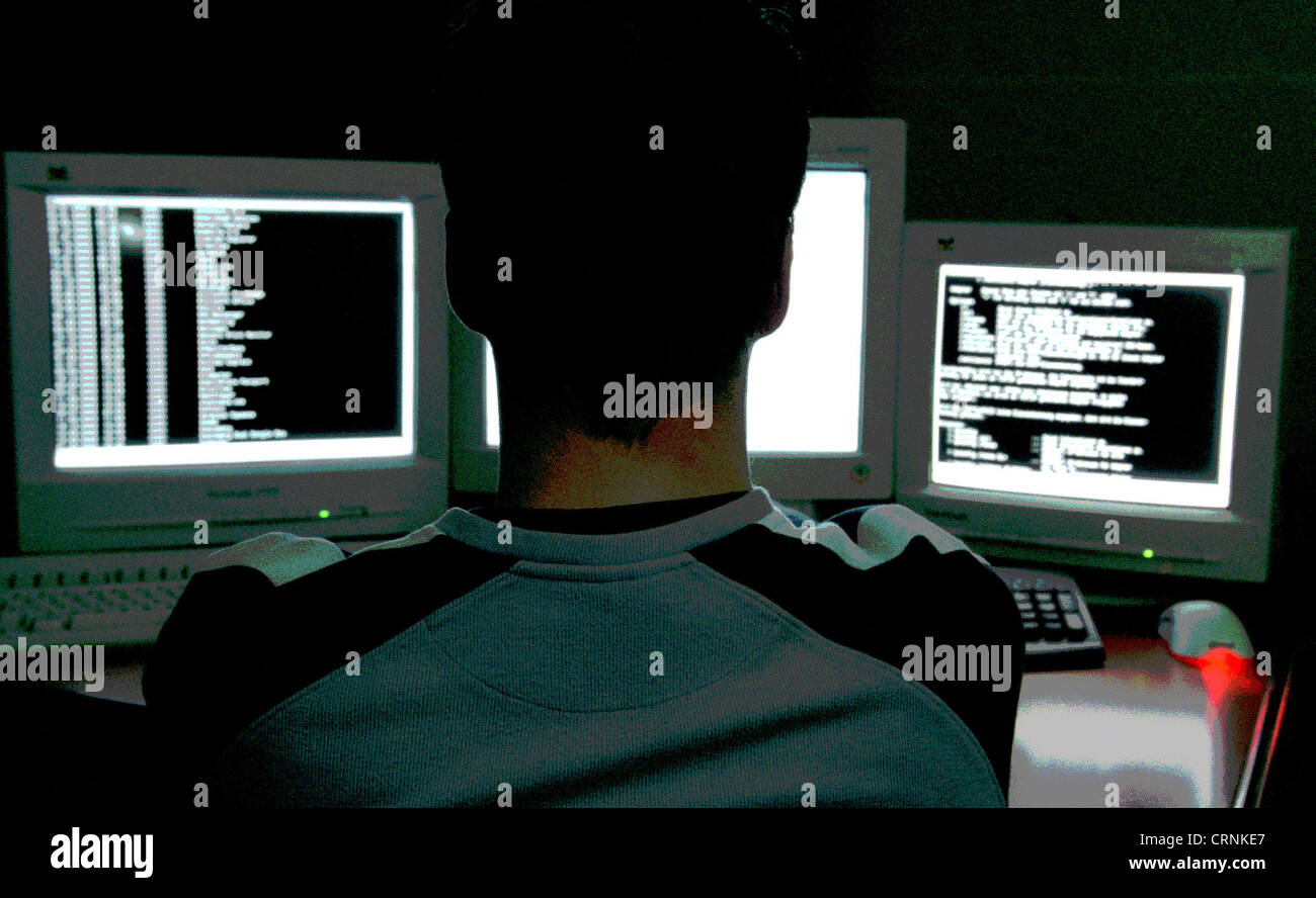 Un giovane uomo seduto nella parte anteriore del monitor per computer Foto Stock