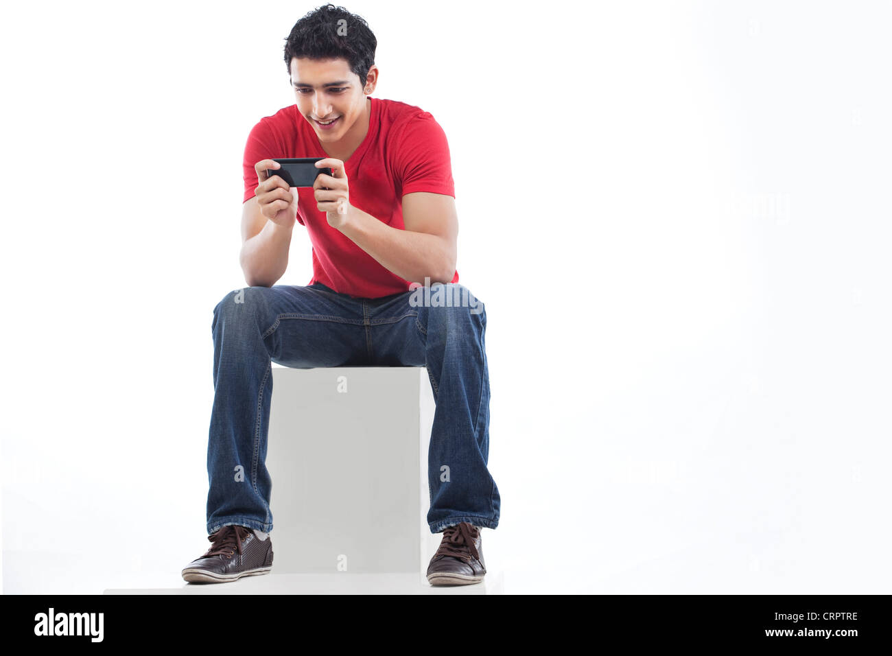 Lunghezza completa di un uomo utilizzando il telefono per la messaggistica di testo contro uno sfondo bianco Foto Stock