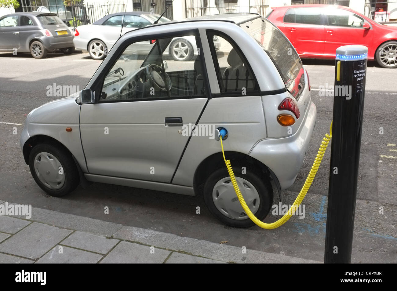 Un'auto elettrica G-Wiz collegata a un punto di ricarica in Hinde Street Westminster, Londra Regno Unito Foto Stock