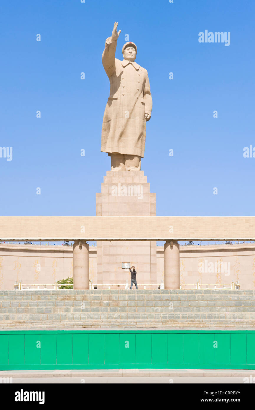 Un turista è sopraffatte come fotografa la statua dell ex leader cinese Mao Zedong di fronte alla piazza della città di Kashgar. Foto Stock