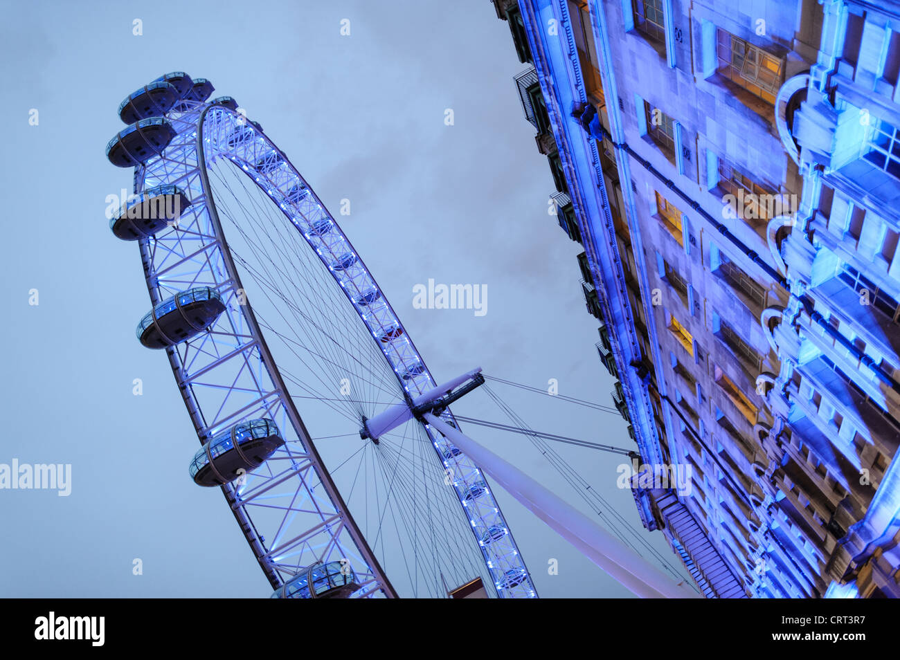 Il London Eye al crepuscolo con edifici. Il London Eye (precedentemente noto come il Millennium Wheel) al crepuscolo contro un cielo nuvoloso. Foto Stock