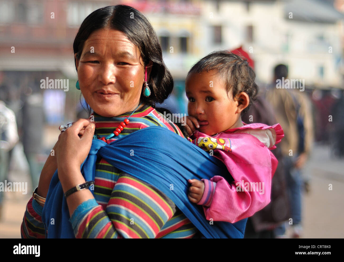 Il nepalese madre indossando vestiti tradizionali porta la sua bambina presso la Santa Sede Boudhanath, Kathmandu Foto Stock