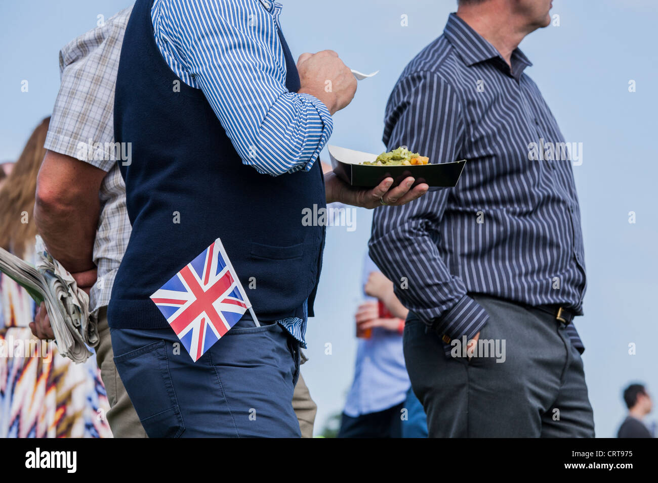 Epsom Derby festival-goer con Unione Jack mangia pesce e patatine fritte Foto Stock