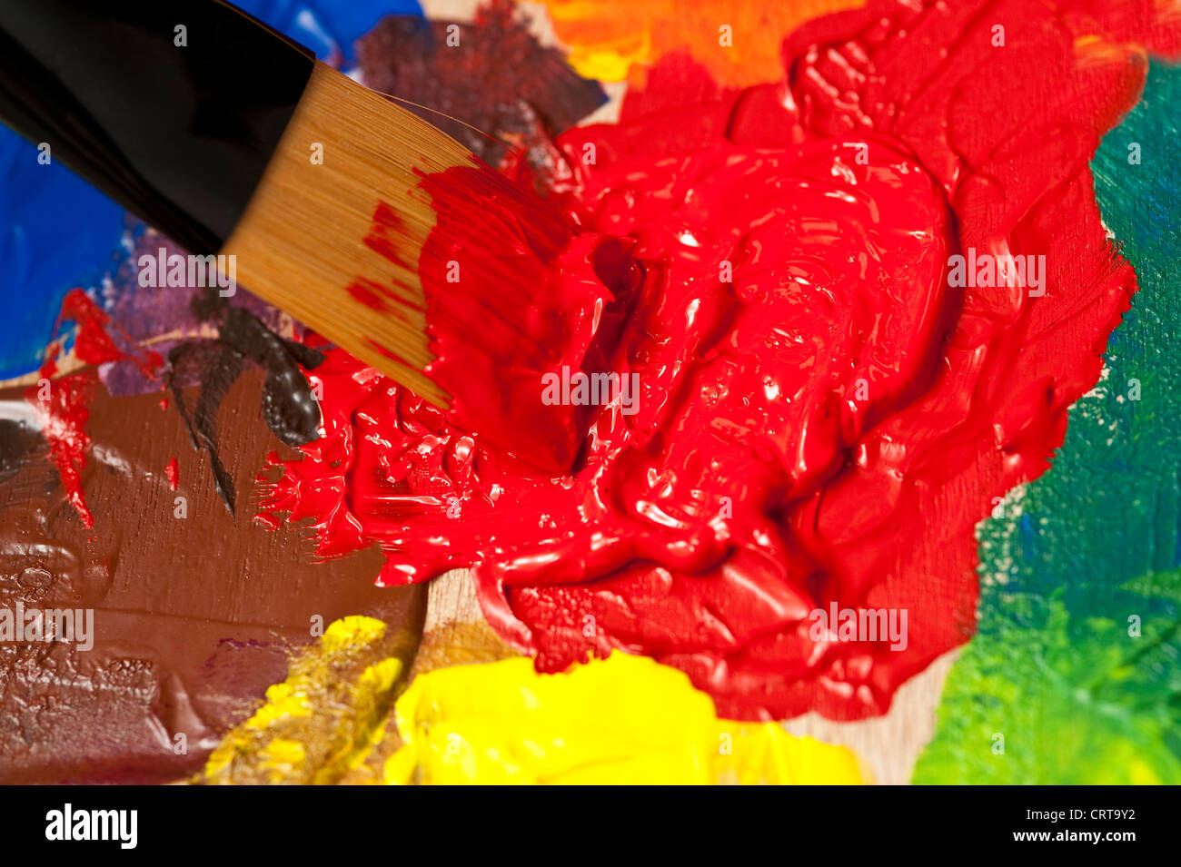 Tavolozza multicolore e spazzola di vernice durante la verniciatura di miscelazione Foto Stock