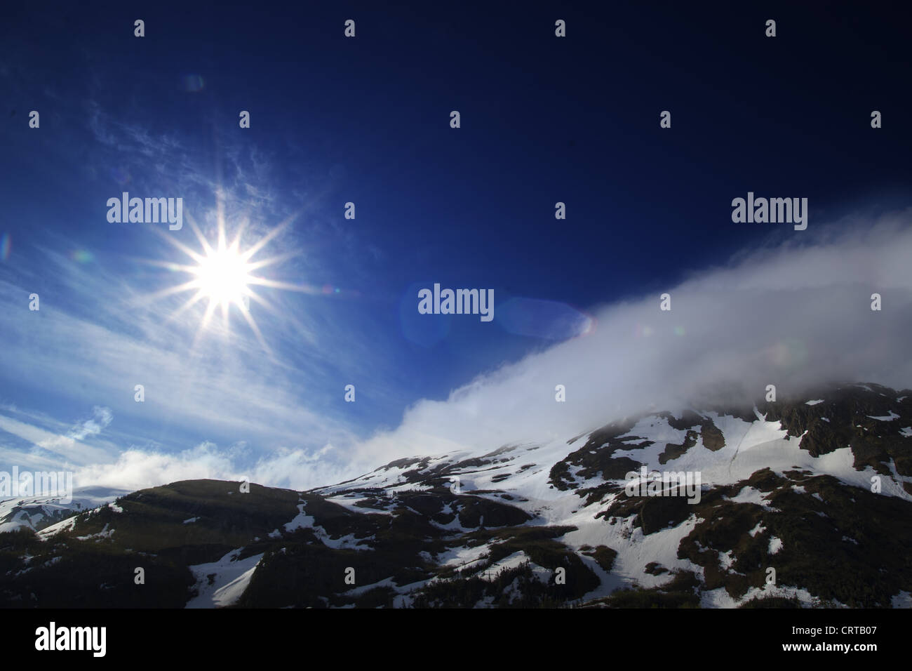 Squarcio nel cielo blu su picchi di montagna in Alaska con la neve e le nuvole. Foto Stock